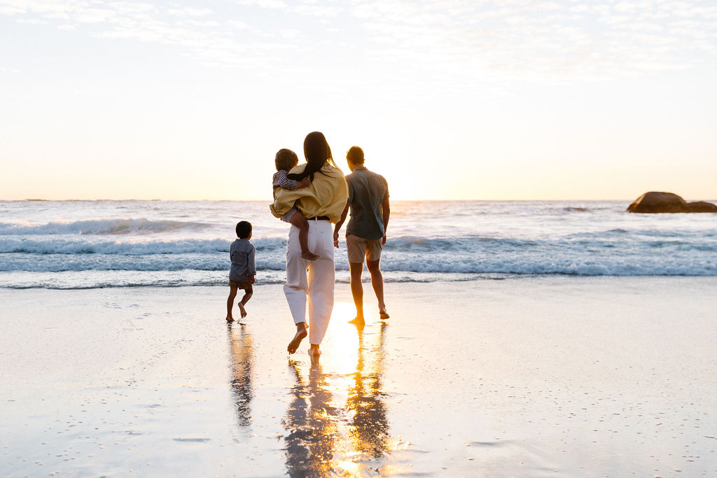 family walking on beach at sunset
